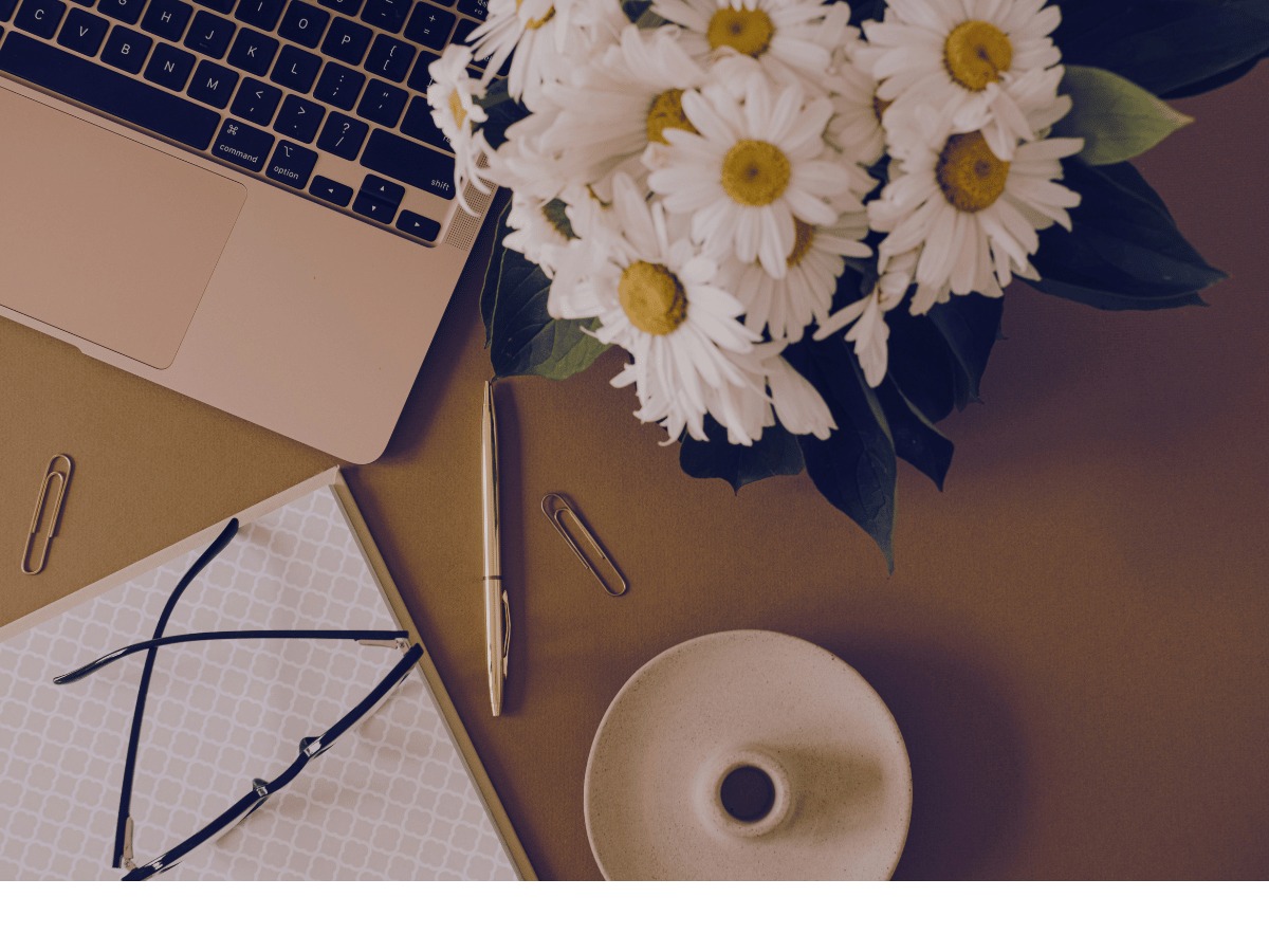 Open mac, flowers and notebook flatlay for post about interior designer website content must-haves list